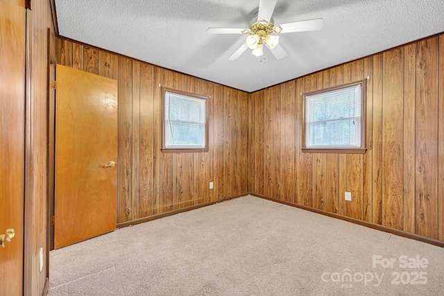 carpeted spare room featuring ceiling fan, a textured ceiling, and a healthy amount of sunlight