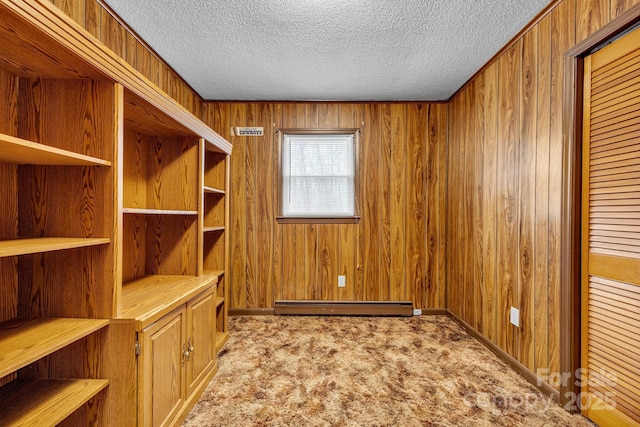 unfurnished office with wood walls, a textured ceiling, light carpet, and a baseboard heating unit