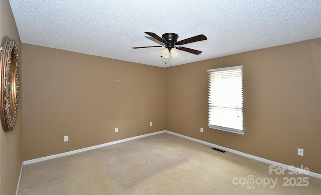 carpeted spare room featuring ceiling fan and a textured ceiling