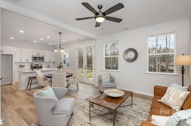 living room with light wood-style flooring, recessed lighting, visible vents, and baseboards