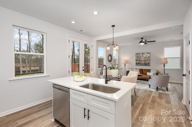 kitchen featuring a sink, white cabinets, light countertops, stainless steel dishwasher, and an island with sink