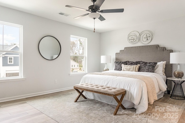 bedroom featuring light wood-style floors, baseboards, visible vents, and ceiling fan