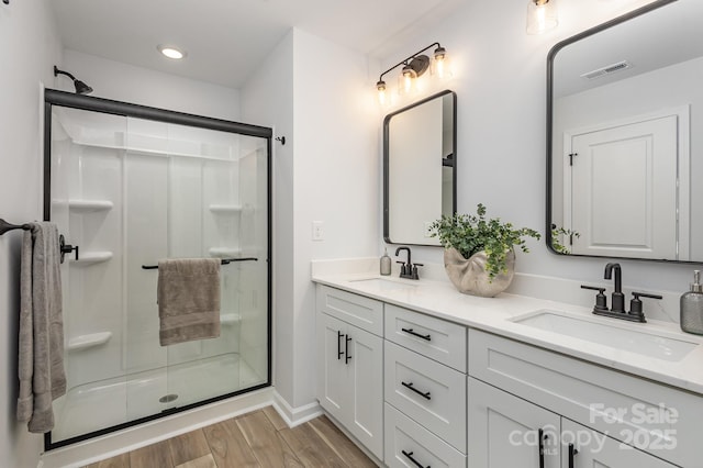 full bathroom featuring visible vents, a sink, a shower stall, and wood finished floors