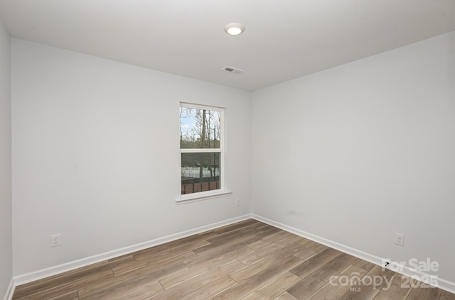 spare room with visible vents, baseboards, and wood finished floors