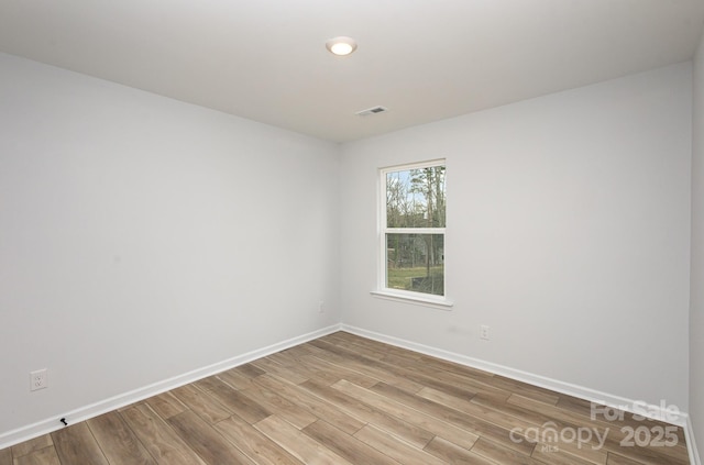 unfurnished room with light wood-type flooring, visible vents, and baseboards