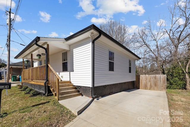 view of front of house with a front yard, covered porch, fence, and crawl space