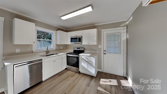 kitchen with appliances with stainless steel finishes, sink, white cabinets, crown molding, and light wood-type flooring