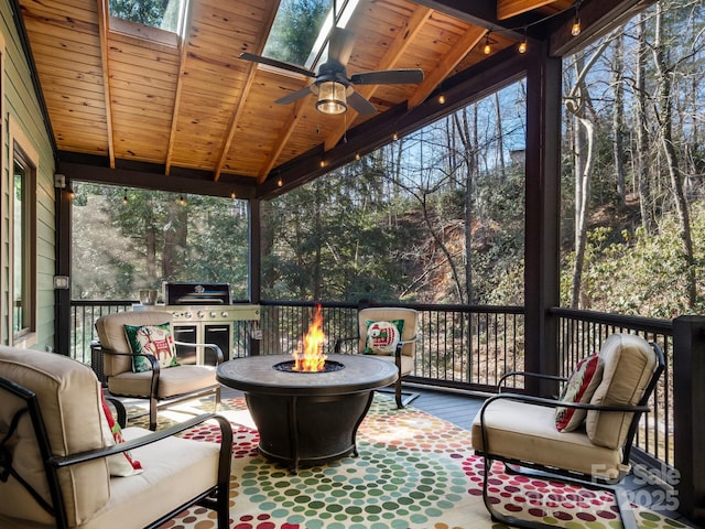 sunroom / solarium with ceiling fan, vaulted ceiling with skylight, and wood ceiling