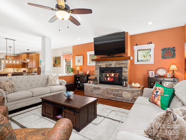 living room featuring ceiling fan, a fireplace, and light hardwood / wood-style flooring