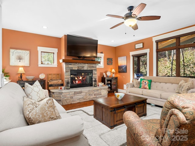 living room featuring a stone fireplace and ceiling fan