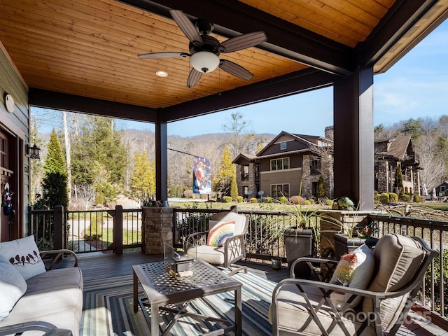 wooden deck with ceiling fan, an outdoor hangout area, and a mountain view