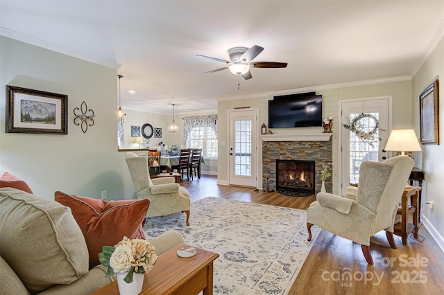 living room featuring crown molding, wood-type flooring, ceiling fan, and a fireplace