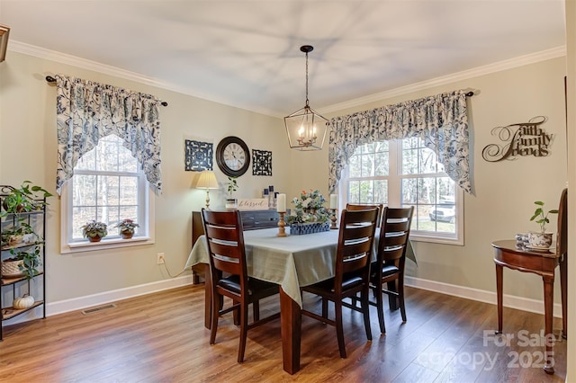 dining area with crown molding, hardwood / wood-style floors, and a notable chandelier