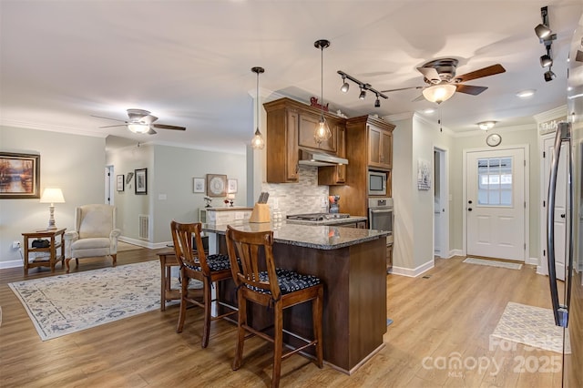 kitchen with pendant lighting, a breakfast bar, stainless steel appliances, ornamental molding, and kitchen peninsula