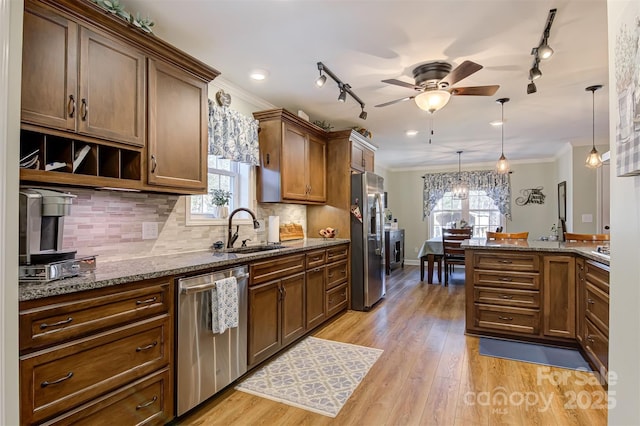 kitchen with appliances with stainless steel finishes, sink, dark stone countertops, and decorative light fixtures