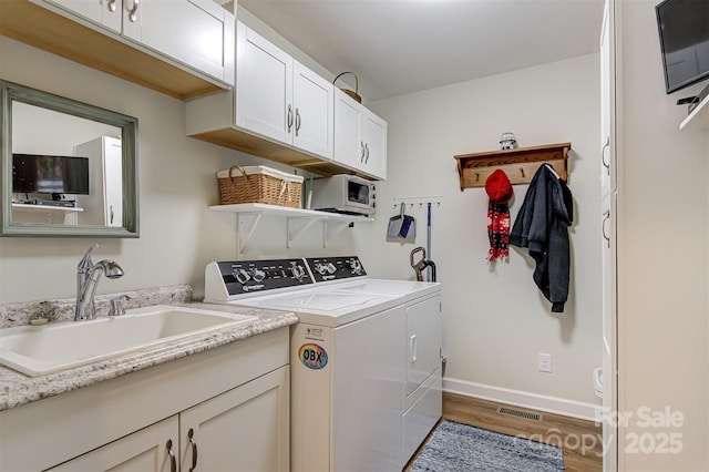 clothes washing area featuring sink, cabinets, light hardwood / wood-style floors, and independent washer and dryer