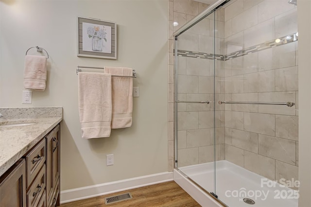 bathroom with hardwood / wood-style flooring, vanity, and a shower with shower door