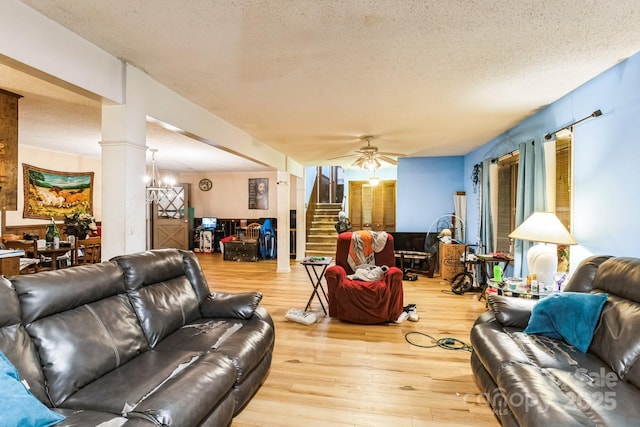 living room featuring ornate columns, ceiling fan, hardwood / wood-style flooring, and a textured ceiling