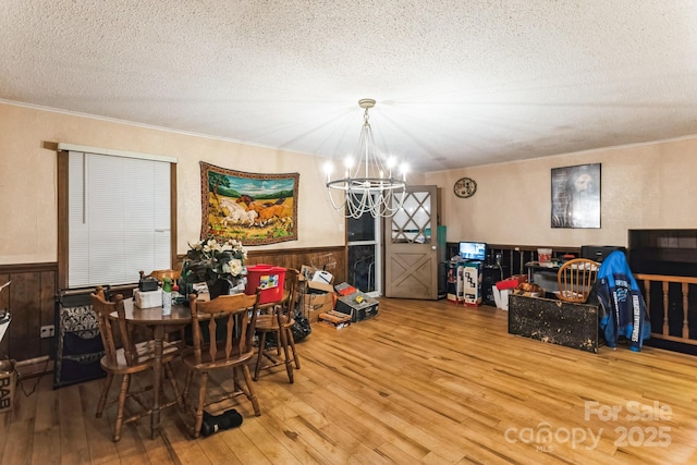 dining space with hardwood / wood-style flooring, ornamental molding, a chandelier, and a textured ceiling