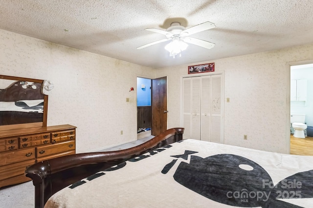 bedroom with a closet, ceiling fan, a textured ceiling, and ensuite bath