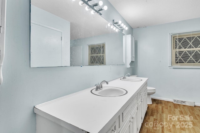 bathroom featuring vanity, toilet, hardwood / wood-style floors, and a textured ceiling