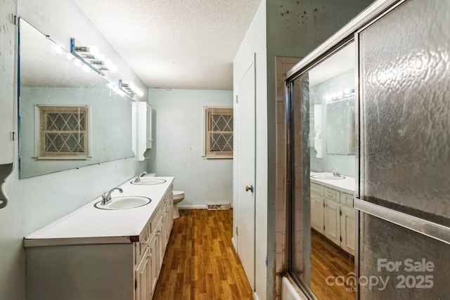 bathroom featuring wood-type flooring, vanity, a textured ceiling, and toilet