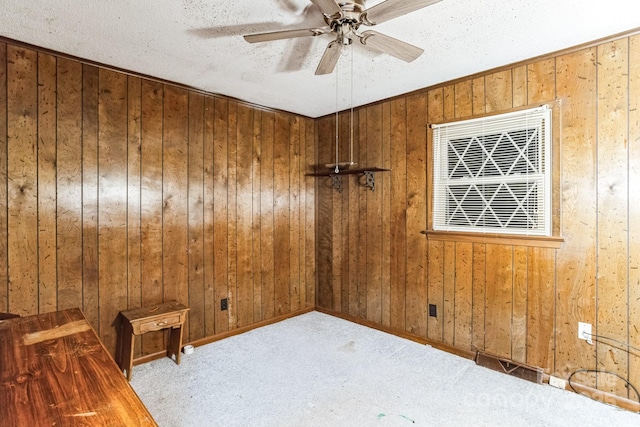 unfurnished room with ceiling fan, wooden walls, light carpet, and a textured ceiling