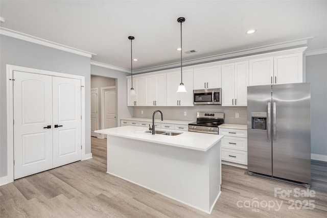 kitchen featuring stainless steel appliances, a center island with sink, sink, and pendant lighting