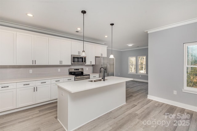 kitchen with sink, decorative light fixtures, an island with sink, stainless steel appliances, and white cabinets