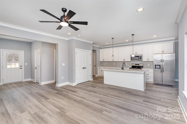 kitchen featuring pendant lighting, white cabinetry, sink, stainless steel appliances, and a center island with sink