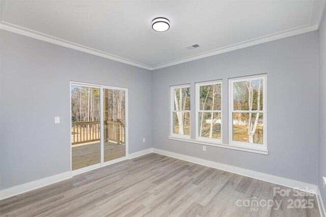 spare room featuring visible vents, crown molding, light wood-style flooring, and baseboards