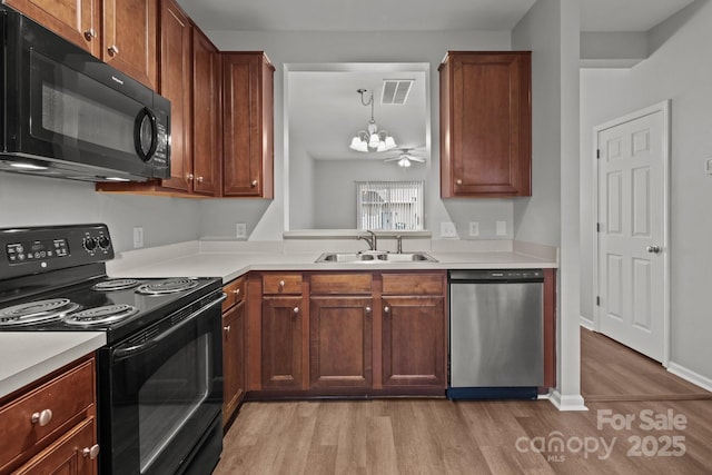 kitchen with pendant lighting, sink, black appliances, and light hardwood / wood-style floors