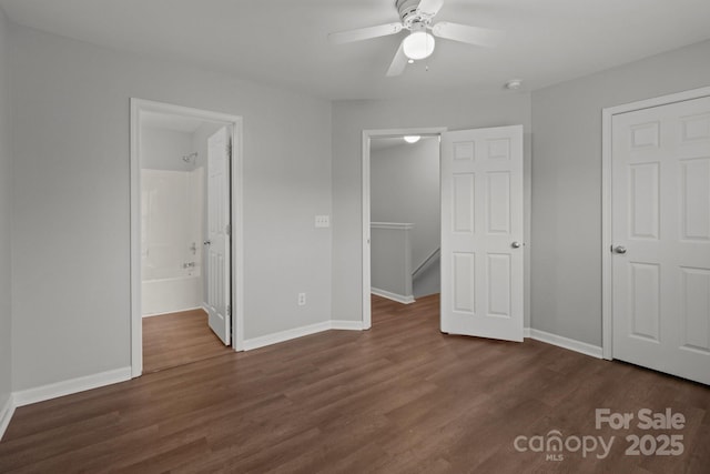 unfurnished bedroom featuring connected bathroom, a walk in closet, dark hardwood / wood-style floors, and ceiling fan