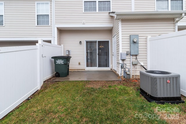 rear view of house with central AC, a patio area, and a lawn