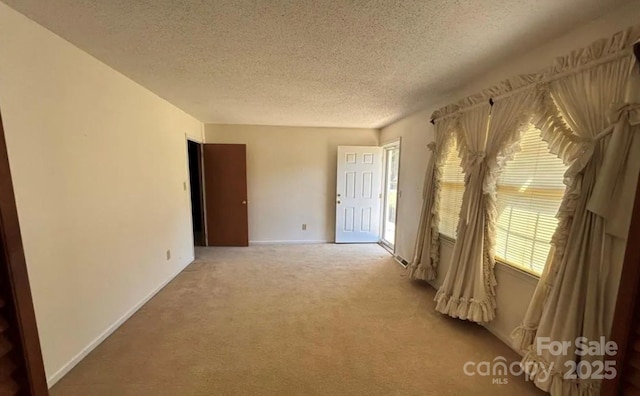 empty room with light colored carpet and a textured ceiling