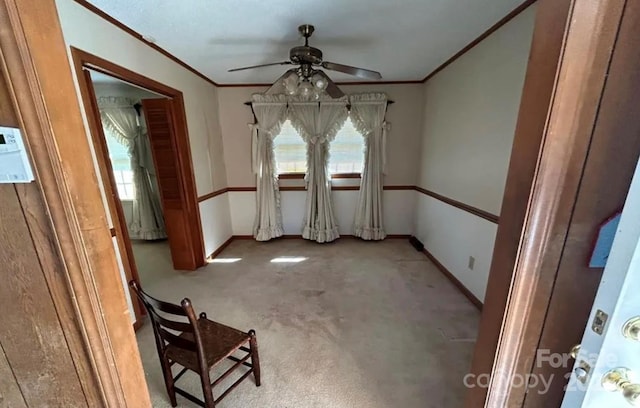 unfurnished dining area with ceiling fan, light colored carpet, and ornamental molding