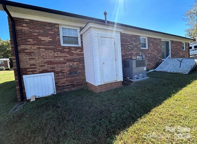 rear view of property with cooling unit and a yard