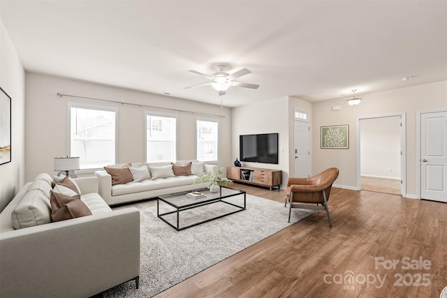living room featuring ceiling fan, baseboards, and wood finished floors