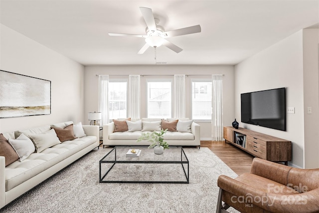 living area with a ceiling fan, wood finished floors, and a healthy amount of sunlight