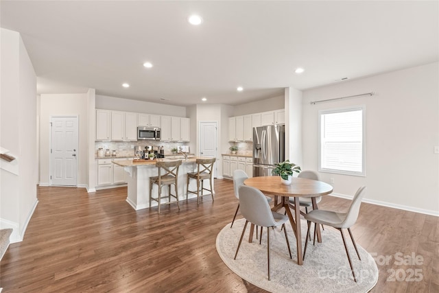 dining space featuring recessed lighting, wood finished floors, and baseboards