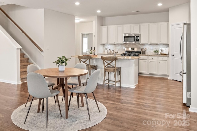 dining area featuring stairway, baseboards, wood finished floors, and recessed lighting