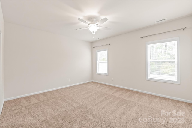 empty room with baseboards, visible vents, carpet floors, and ceiling fan