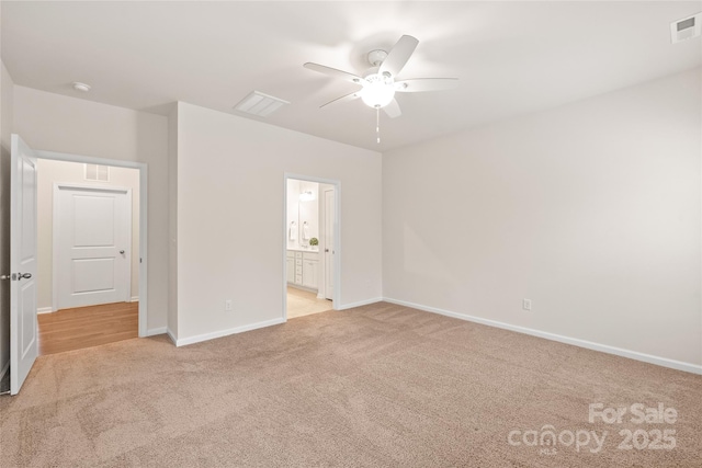 unfurnished bedroom featuring ensuite bath, light carpet, baseboards, and visible vents