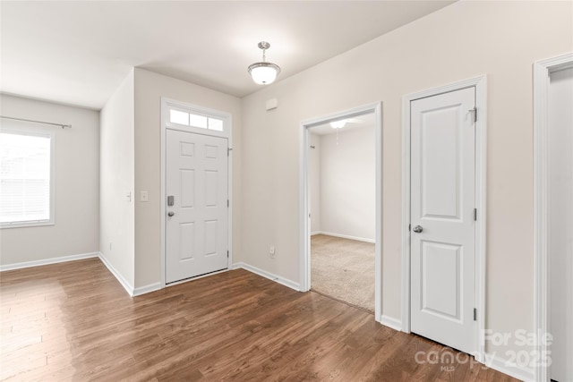 foyer featuring baseboards and dark wood-style flooring
