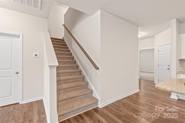 staircase with visible vents, baseboards, and wood finished floors