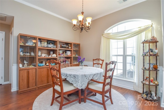 dining room with crown molding, dark hardwood / wood-style floors, and a chandelier