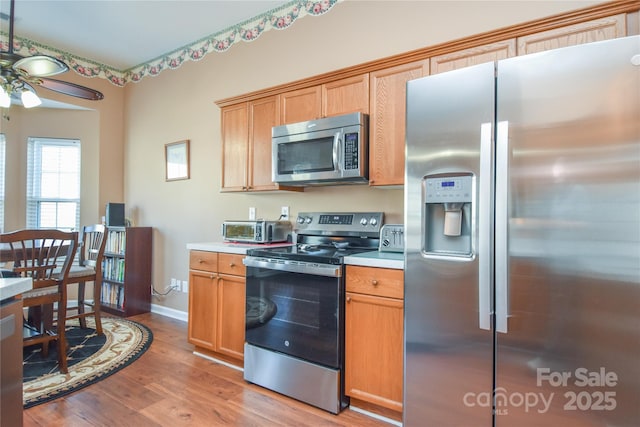 kitchen featuring stainless steel appliances, light hardwood / wood-style floors, and ceiling fan