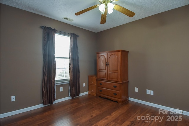 unfurnished bedroom featuring ceiling fan, dark hardwood / wood-style floors, and a textured ceiling