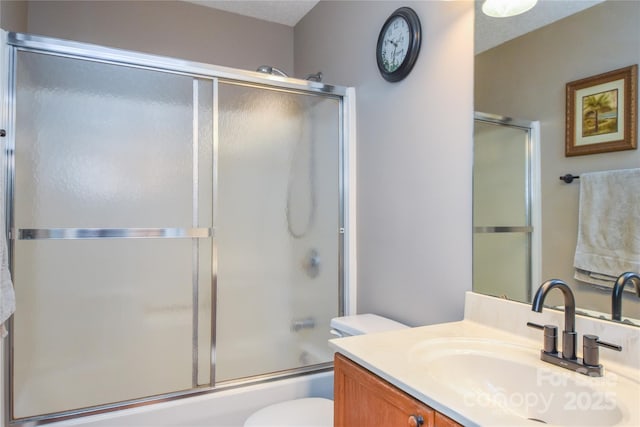 full bathroom with vanity, shower / bath combination with glass door, and toilet