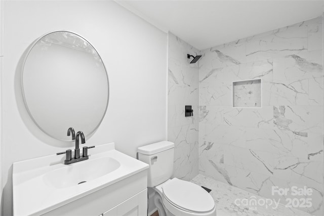 bathroom with vanity, a tile shower, and toilet